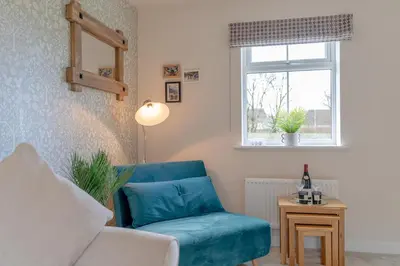 a living room with a blue chair and a window at Foxglove Haven- 3-Bed Detached - Garden - Drive in Longridge