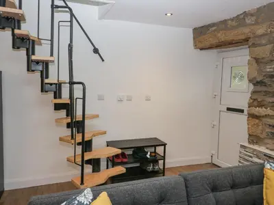 a spiral staircase in a living room with a couch at Cosy Logs Cottage in Grange Over Sands