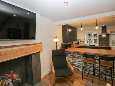 a kitchen with a bar with a tv above it at Cosy Logs Cottage in Grange Over Sands
