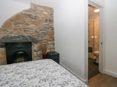 a bedroom with a stone wall and a fireplace at Cosy Logs Cottage in Grange Over Sands