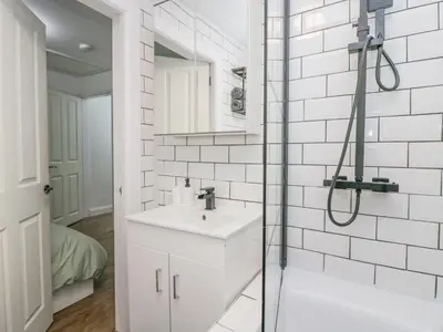 a white bathroom with a sink and a shower at Cosy Logs Cottage in Grange Over Sands