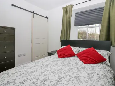 a bedroom with a bed with two red pillows at Cosy Logs Cottage in Grange Over Sands