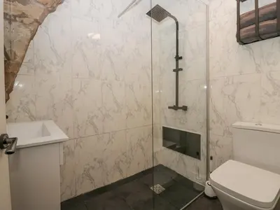 a bathroom with a shower with a toilet and a sink at Cosy Logs Cottage in Grange Over Sands