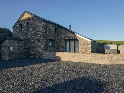 a stone house with a stone wall on a gravel driveway at Apple Tree Barn in Dalton in Furness