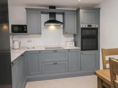 a kitchen with gray cabinets and a stove top oven at Apple Tree Barn in Dalton in Furness