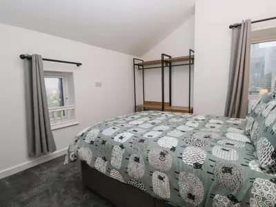 a bedroom with a bed with a green and white bedspread at Apple Tree Barn in Dalton in Furness