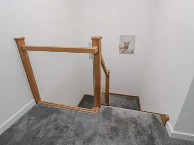 a stairwell with a wooden rail and a white wall at Apple Tree Barn in Dalton in Furness