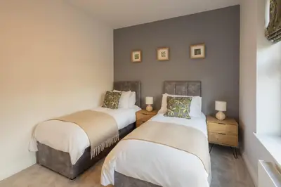 two twin beds in a room with a wall at Host & Stay - Bay View House in Grange Over Sands