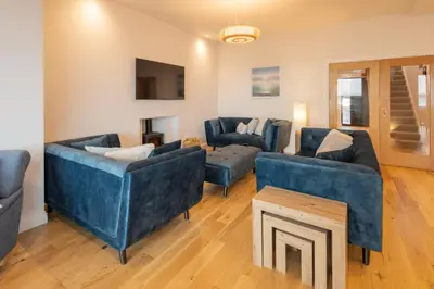 a living room with blue couches and a tv at Host & Stay - Bay View House in Grange Over Sands