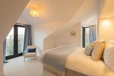 a bedroom with a bed and a chair and windows at Host & Stay - Bay View House in Grange Over Sands