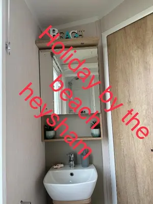 a bathroom with a white sink and a mirror at Holiday escapes by the bay in Heysham
