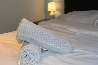 a white bed with a rolled up towel on it at Beautiful home near beach in Formby