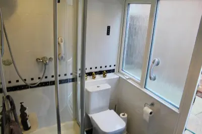a bathroom with a toilet and a glass shower at Beautiful home near beach in Formby