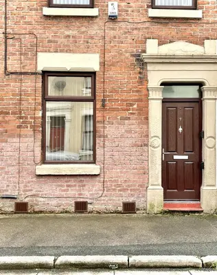 a brick building with a brown door and two windows at Modernised 3-bed home in Bamber Bridge, Preston in Bamber Bridge