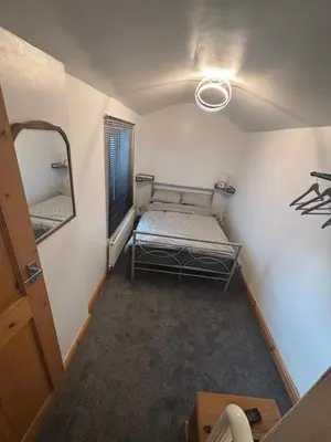 a small room with a bed and a mirror at Morecambe Bay Cottage in Morecambe