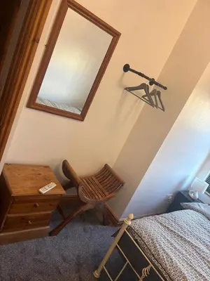 a bedroom with a mirror and a chair next to a bed at Morecambe Bay Cottage in Morecambe