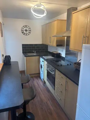 a kitchen with wooden cabinets and a stove top oven at Morecambe Bay Cottage in Morecambe