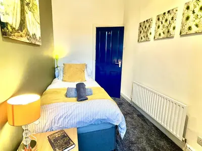 a small bedroom with a bed with a blue door at Ideal 4-bed stay-away-home sleeps 6 in Preston in Preston