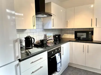a kitchen with white cabinets and black appliances at Ideal 4-bed stay-away-home sleeps 6 in Preston in Preston