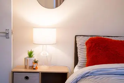 a bed with a red pillow and a lamp on a night stand at Silvester Residence in Liverpool