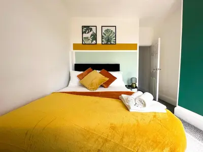 a bedroom with a yellow bed with towels on it at Liverpool Serviced Apartment - Phillimore in Liverpool