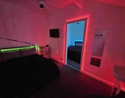 a bedroom with a bed and a red lighted mirror at Hotel Claytou in Blackpool