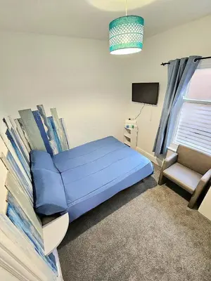 a bedroom with a blue bed and a chair at Hotel Claytou in Blackpool