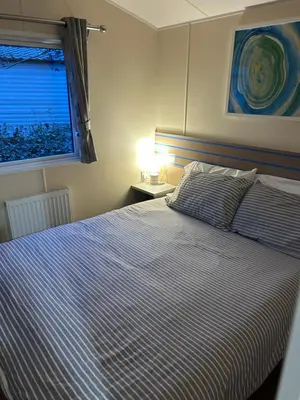 a bedroom with a bed with a blue and white striped blanket at Haven Cala gran 2026 spring summer autumn winter breaks up to January 2027 A full action camp for all ages disabled friendly Fleetwood Blackpool Entire home 6 people seaside caravan park in Fleetwood