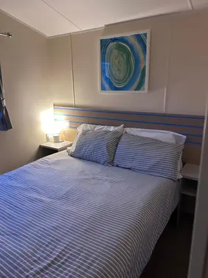 a bedroom with a bed with a blue and white striped blanket at Haven Cala gran 2026 spring summer autumn winter breaks up to January 2027 A full action camp for all ages disabled friendly Fleetwood Blackpool Entire home 6 people seaside caravan park in Fleetwood