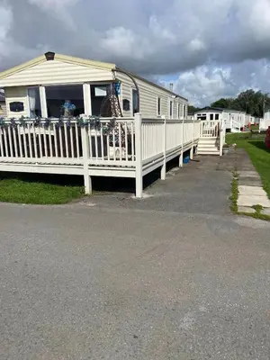 a white house with a porch and a white fence at Haven Lakeland Caravan Hire in the Lake District in Flookburgh