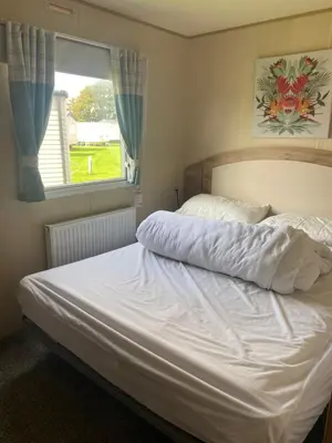 a bedroom with a white bed with a window at Haven Lakeland Caravan Hire in the Lake District in Flookburgh