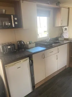 a kitchen with white cabinets and a counter top at Haven Lakeland Caravan Hire in the Lake District in Flookburgh