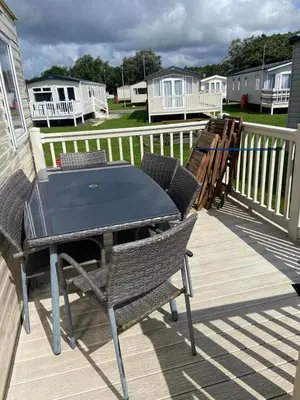 a table and chairs on a deck with houses at Haven Lakeland Caravan Hire in the Lake District in Flookburgh