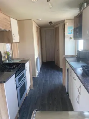 a kitchen with white appliances and a wooden floor at Haven Lakeland Caravan Hire in the Lake District in Flookburgh