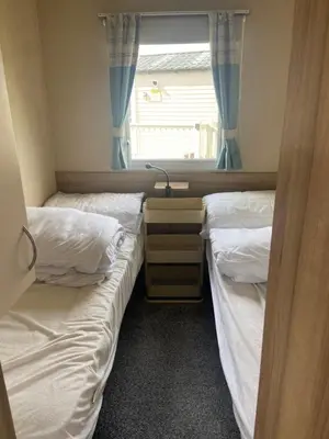 two twin beds in a room with a window at Haven Lakeland Caravan Hire in the Lake District in Flookburgh