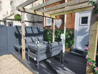 a wooden pergola with a bench on a deck at Beachview apartment in Cleveleys