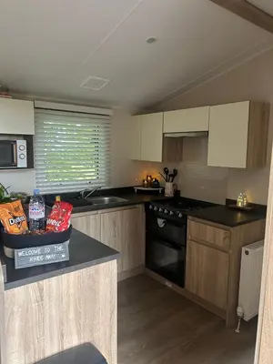 a kitchen with wooden cabinets and a black stove top oven at Hideaway Ribble Valley in Preston