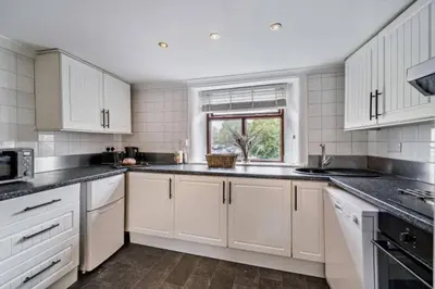 a kitchen with white cabinets and a window at Quarter Deck in Ulverston