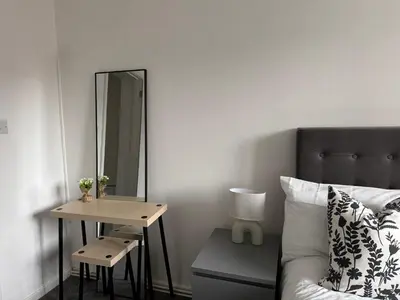 a bedroom with a bed and a mirror and a table at Gertrude house in Saint Helens