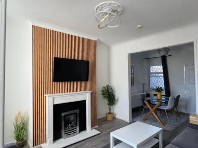 a living room with a fireplace with a tv above it at Gertrude house in Saint Helens