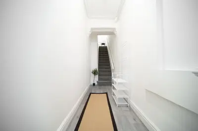 a hallway with white walls and stairs with a rug at Spacious Duplex Apartment - Perfectly Situated in the Heart of the City in Blackpool