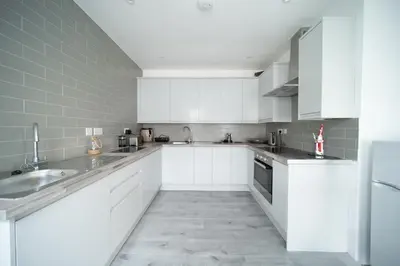 a white kitchen with white cabinets and appliances at Spacious Duplex Apartment - Perfectly Situated in the Heart of the City in Blackpool