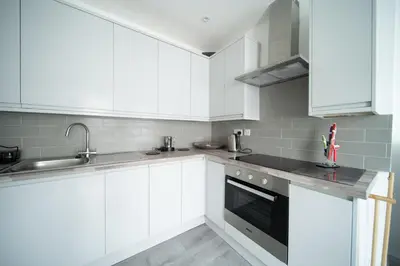 a white kitchen with white cabinets and a sink at Spacious Duplex Apartment - Perfectly Situated in the Heart of the City in Blackpool