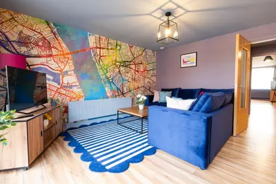 a living room with a blue couch and a large mural at City centre two bedroom apartment in the heart of Liverpool in Liverpool
