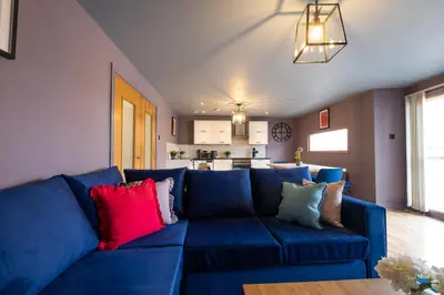 a blue couch with colorful pillows in a living room at City centre two bedroom apartment in the heart of Liverpool in Liverpool