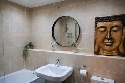 a bathroom with a sink and a mirror with a face on the wall at City centre two bedroom apartment in the heart of Liverpool in Liverpool