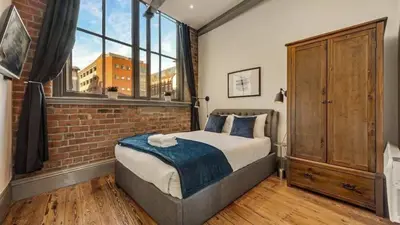 a bedroom with a bed and a brick wall at Central Warehouse Apt - Sleeps 8, Pet Friendly in Liverpool