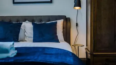 a bed with blue and white pillows and a lamp at Central Warehouse Apt - Sleeps 8, Pet Friendly in Liverpool