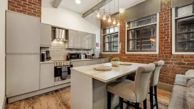 a kitchen with a table and a brick wall at Central Warehouse Apt - Sleeps 8, Pet Friendly in Liverpool