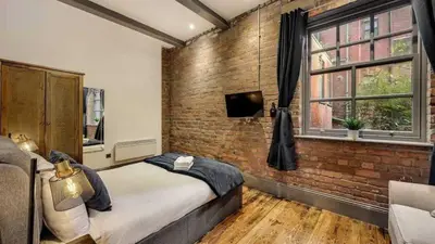 a bedroom with a brick wall and a bed at Central Warehouse Apt - Sleeps 8, Pet Friendly in Liverpool